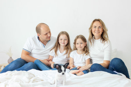 Lovely parents and their daughters having fun on a bed indoorsの写真素材