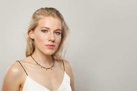 Posing young blond female model with clear skin, soft make-up and healthy hair and natural emotional expression portrait shot. Blonde woman on white backgroundの写真素材