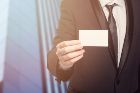 A man in a suit holding a white business card. Concept of professionalism and formalityの写真素材