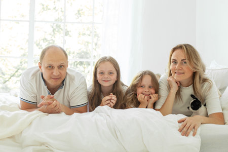 Portrait of parents and their daughters having fun on a bed indoorsの写真素材