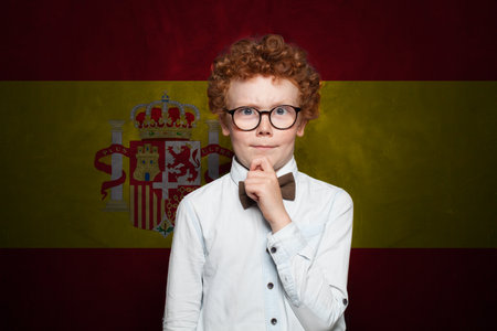 Thinking child boy in school uniform on Spanish flag background. Education and childhood in Spain conceptの写真素材