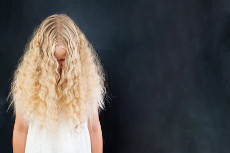 Blond girl with long wavy healthy hair on black backgroundの写真素材