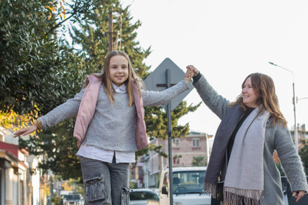 Happy woman and young girl child walking along the streets of the city. Childhood, happiness, vacation, family and leisure activity conceptの写真素材