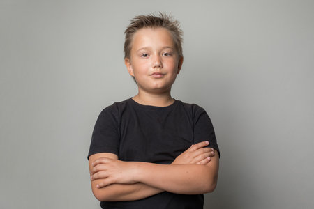 Happy child portrait. Little kid boy standing with crossed arms on white backgroundの写真素材