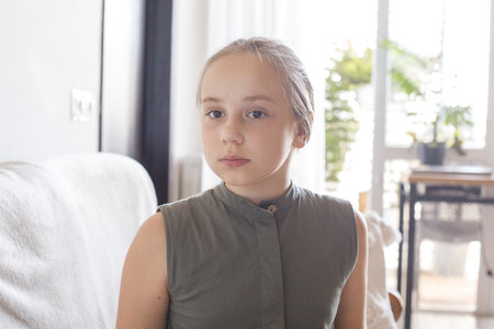 Beautiful young girl child 10 years old sitting on cozy sofa, relaxing at home. Love, bonding and...