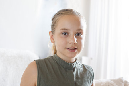 Happy young girl child 10 years old sitting on cozy sofa, relaxing at home. Love, bonding and...