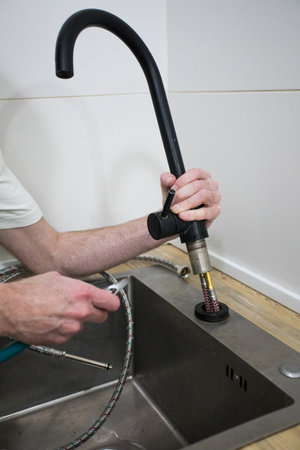 Plumber repair water tap in kitchen. Repair service concept.の写真素材
