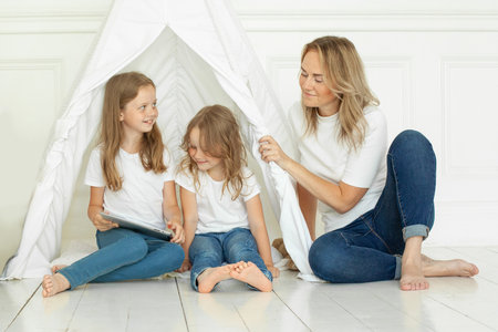 Happy mother and two daughters. Family using tablet gadget at homeの写真素材