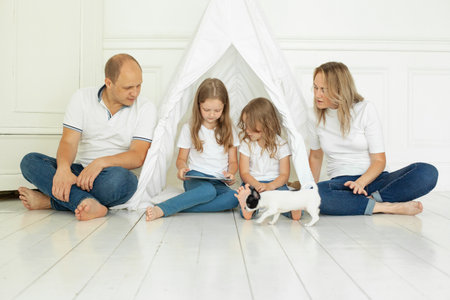 Happy family mother father and children using tablet gadget sitting on floor at homeの写真素材