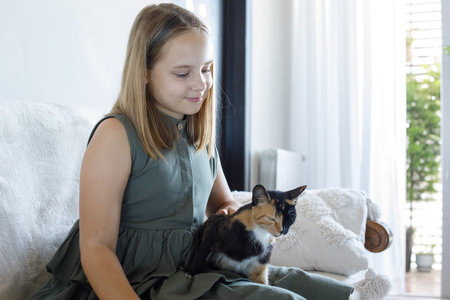 Cute friends. Young child girl with her cat pet companion indoorの写真素材