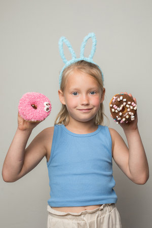 Adorable child girl holding testy donut. Cute little girl with sweet food indoor