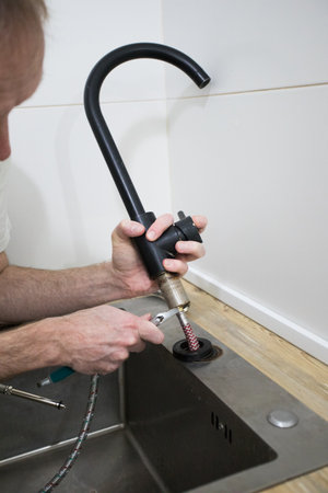 Plumber fixing a problem in the kitchenの写真素材