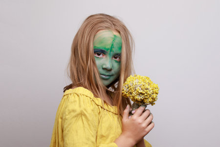 Cute young girl child with green face paint makeup. Halloween ogre lookの写真素材