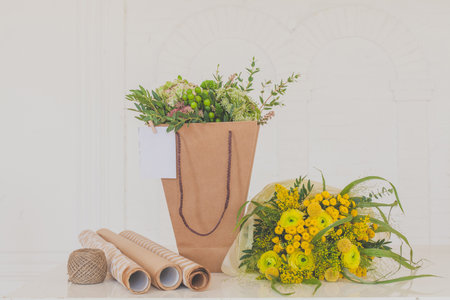 Flowers Summer Present. Flower bouquet in craft paper bag on white backgroundの写真素材