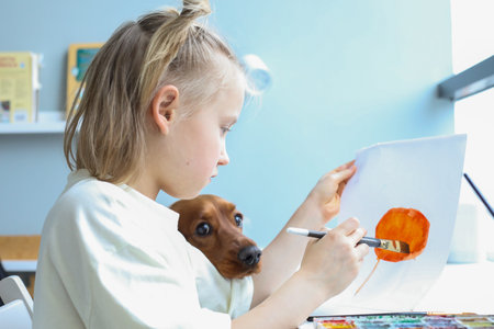 Pretty young child with puppy dog pet painting at homeの写真素材