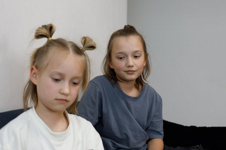 Portrait of 6 and 11 year old sibling. Young brother looking at little sisterの写真素材