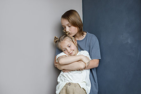 Lovely children little girl and boy together at home. Brother kissing and hugging his sister, family love and childhood conceptの写真素材
