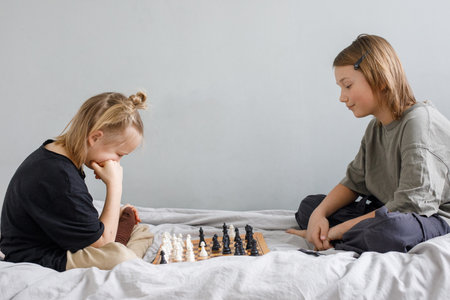 Concentrated clever children with board game having fun. Two cute children playing chess at home