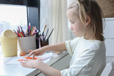 Cute young child painting at home. Close-up portrait of little girl indoor