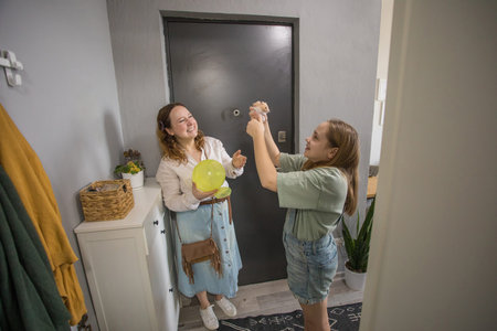 women with daughter are having a fun moment in a home entrance. The door is black and the room has plants.の写真素材