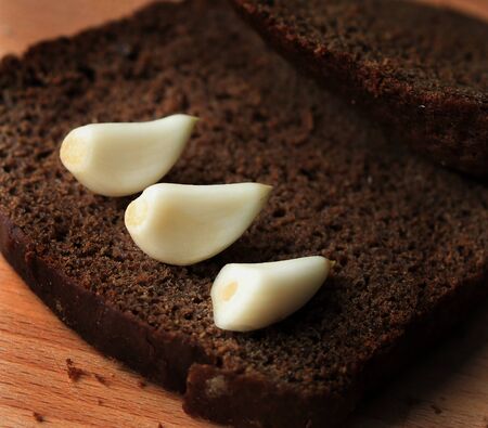 three cloves of garlic on black bread macro photo.の写真素材