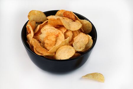 potato chips in a black bowl on a white background.delicious crispy chips. junk foodの写真素材