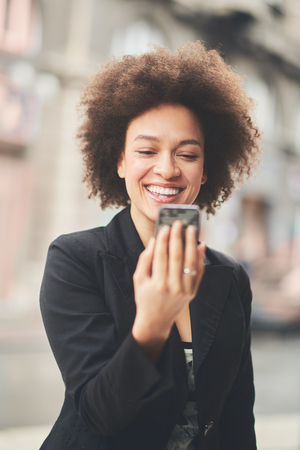 Busy mixedrace woman using smartphone outdoorsの写真素材