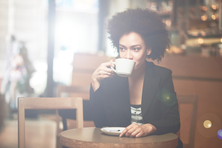 Happy mixed race woman having a coffee in coffee shopの写真素材