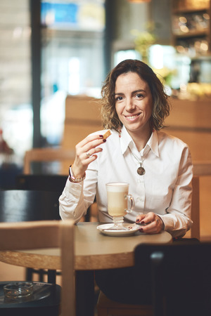 Happy mixed race woman having a coffee in coffee shopの写真素材