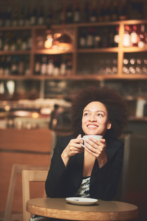 Happy mixed race woman having a coffee in coffee shopの写真素材
