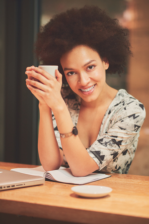 Happy mixed race woman having a coffee in coffee shopの写真素材