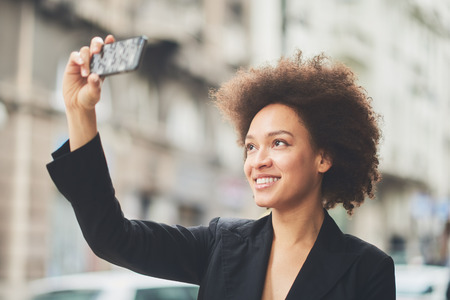Busy girl using smartphone outdoorsの写真素材