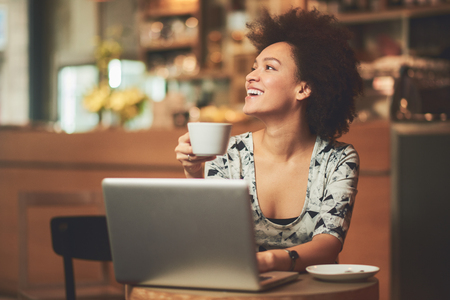 Happy mixed race woman having a coffee in coffee shopの写真素材