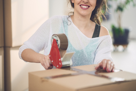 Young Caucasian girl using duct tape for packing carton boxesの写真素材