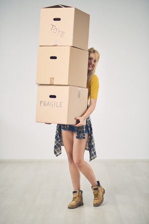 Young Caucasian woman relocating boxes, lots of boxes aroundの写真素材