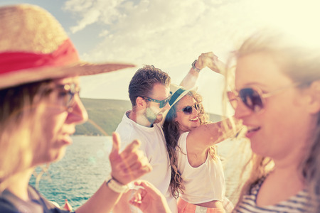 Group of people dancing, chatting and having a good time at beach partyの写真素材