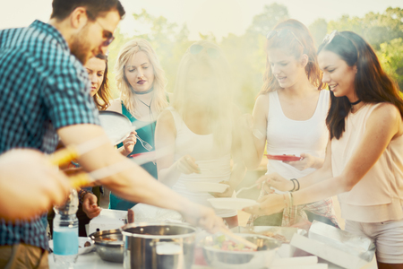 Small group of friends drinking alcohol and having a meal at barbecue partyの写真素材