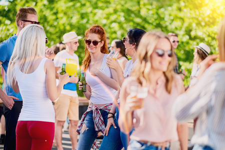 Friends chatting and having good time while standing and drinking alcohol at outdoor party