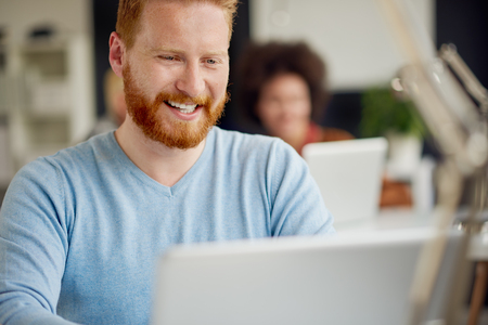 Businessman using laptop in modern office/ part of multi ethnic teamの写真素材