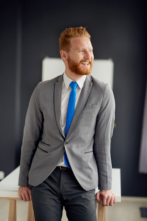 Caucasian businessman standing against the desk in modern officeの写真素材