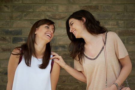 Two girls standing against the wall outdoor and chattingの写真素材