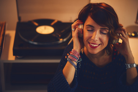 Woman listening vinyl at home. Evening atmosphereの写真素材