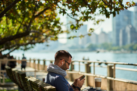 Enjoying city life. Handsome young man having coffee to go. New York city in backgroundの写真素材
