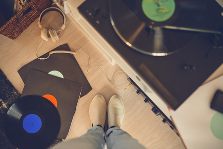 Bird eye view of female legs among vinyl records and gramophoneの写真素材