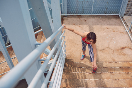 Beautiful young woman in sporty outfit doing some stretching exercises before going for a run in the cityの写真素材