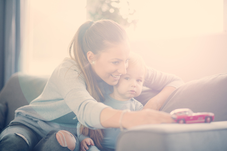 Mom playing with her son in cosy living roomの写真素材