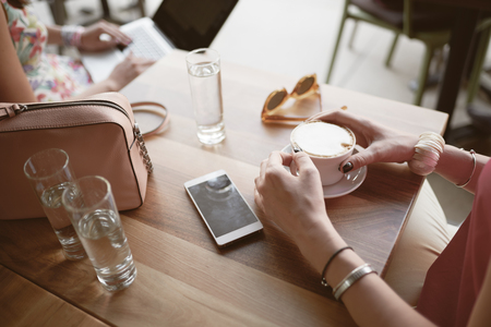 Aerial view of girls drinking coffee and using laptop in cafeの写真素材
