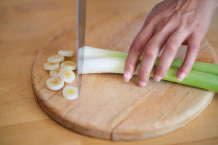 Close up of woman`s hands chopping leekの写真素材