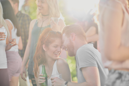 Ginger couple flirting and drinking at outdoor partyの写真素材