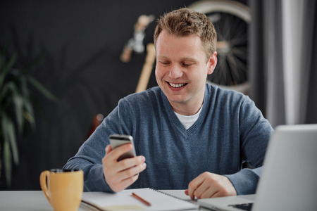 Businessman using smartphone while sitting at personal workspaceの写真素材